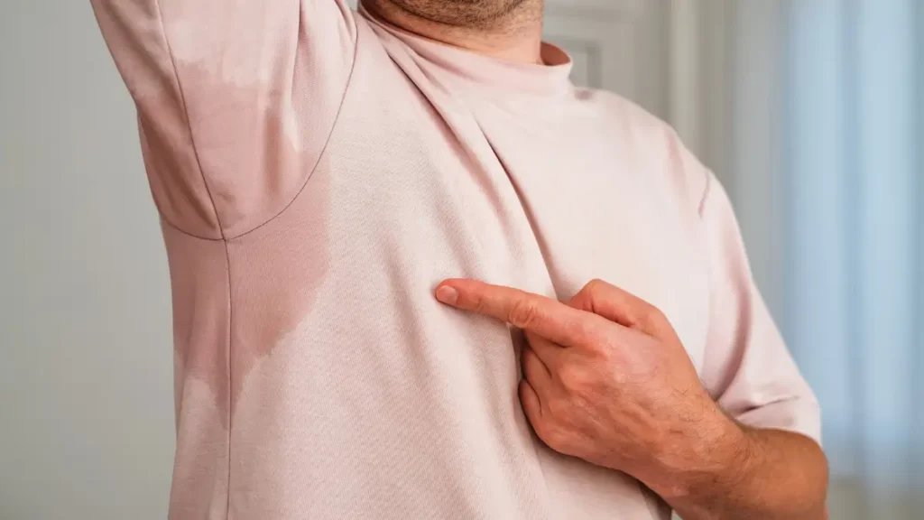 Spocony mężczyzna odczuwający dyskomfort związany z nadmiernym poceniem się