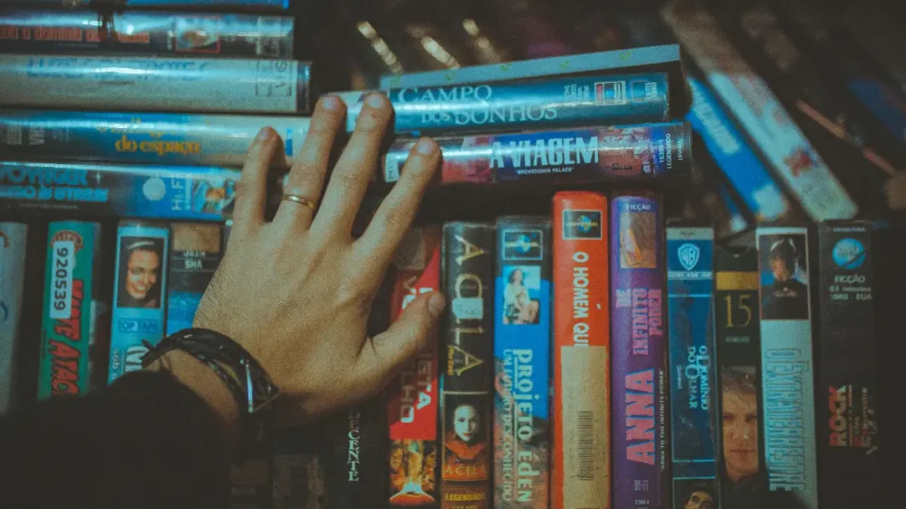 Mężczyzna wybierający stare kasety VHS z horrorami na Halloween, nostalgiczny klimat lat 80
