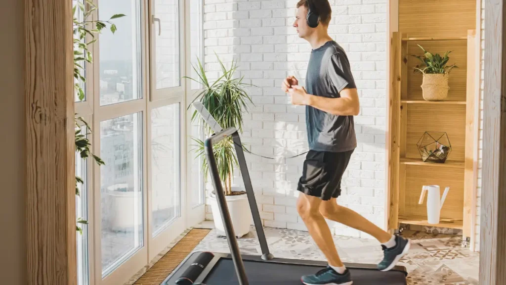 Osoba biegnąca na bieżni podczas treningu cardio w domowej siłowni